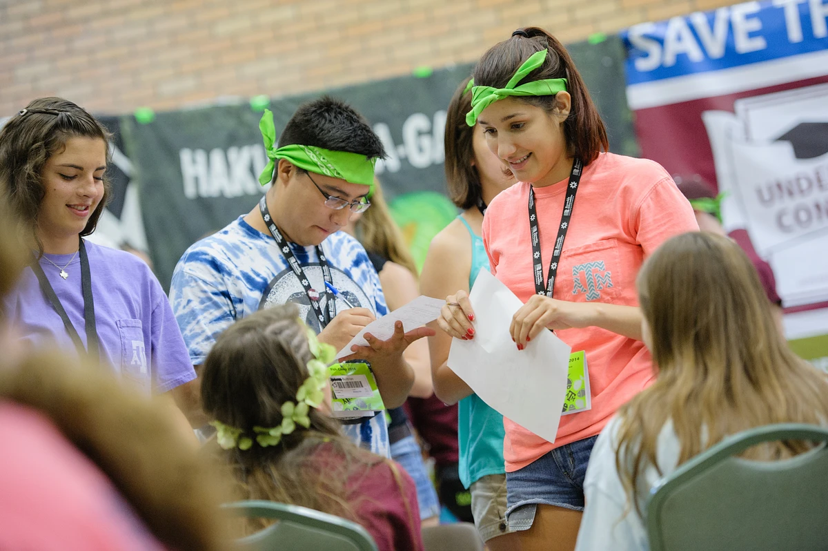 Two students wearing neon green headbands filling out paperwork