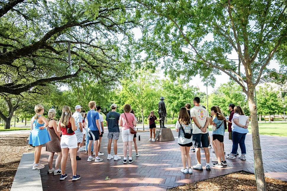 A group of students on a tour with a Howdy Crew leader in Aggie Park.