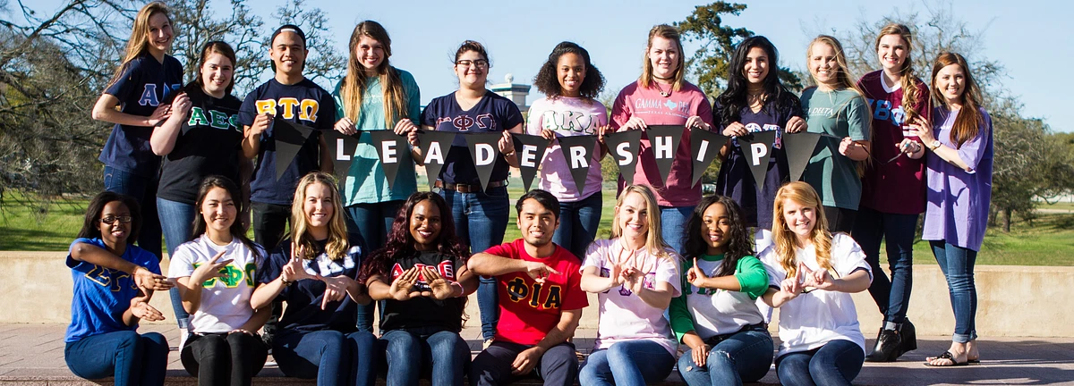A group of students in fraternity and sorority shirts with banner text quote leadership