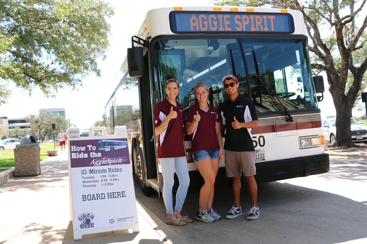 3 student bus drivers standing in front of Aggie Spirit Bus