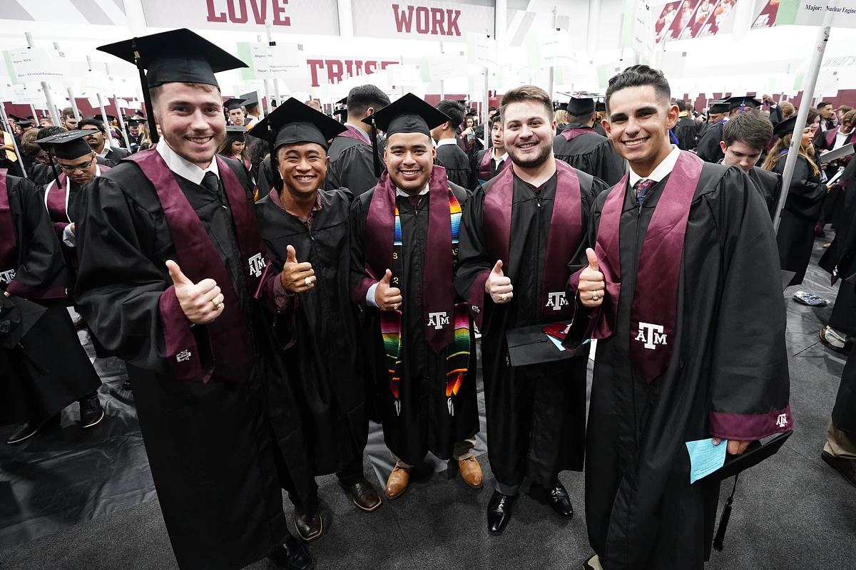 Five students in regalia posing for graduation