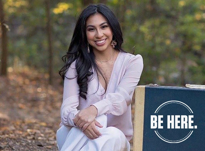 Courtesy photo of Odyssey Olmos '24, with a stack of suitcases with a logo "Be Here."