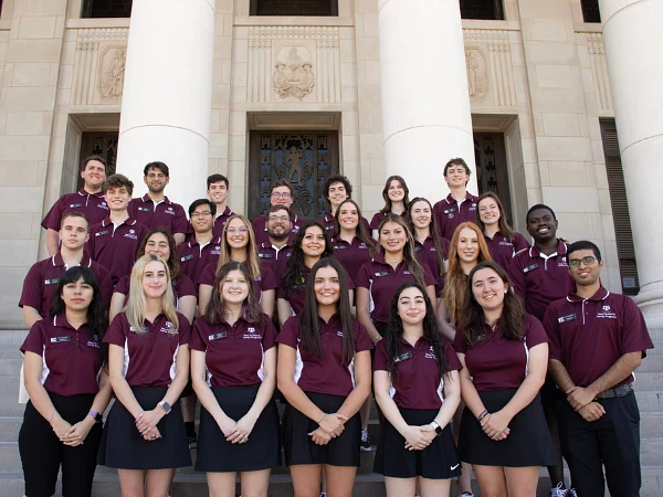 Aggie Orientation Leaders wearing maroon polos in front of the Texas A&M Administration Building