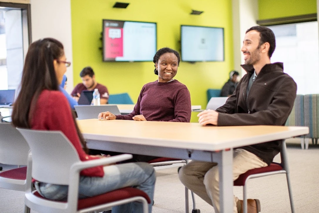 Three students at a table talking