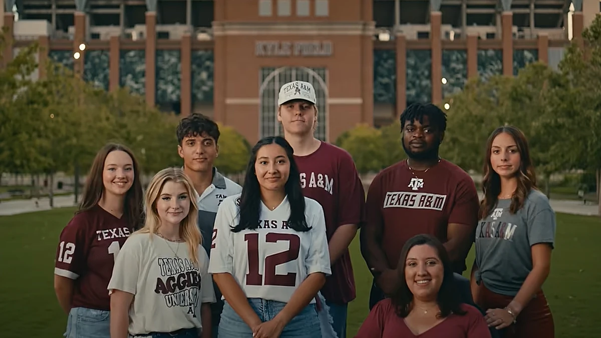 A group of students in Texas A&M attire pose in front of Kyle Field.