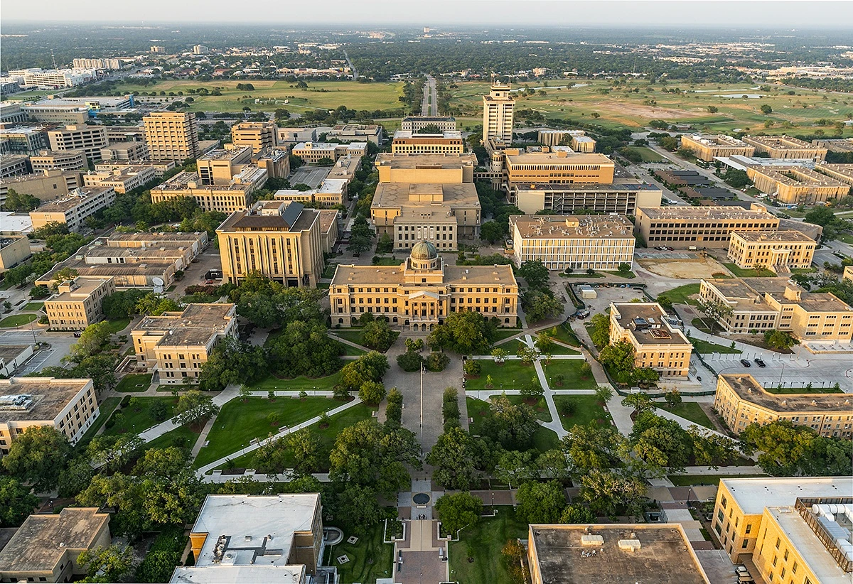 An aerial view of a large campus with numerous buildings, trees, and well-organized pathways.