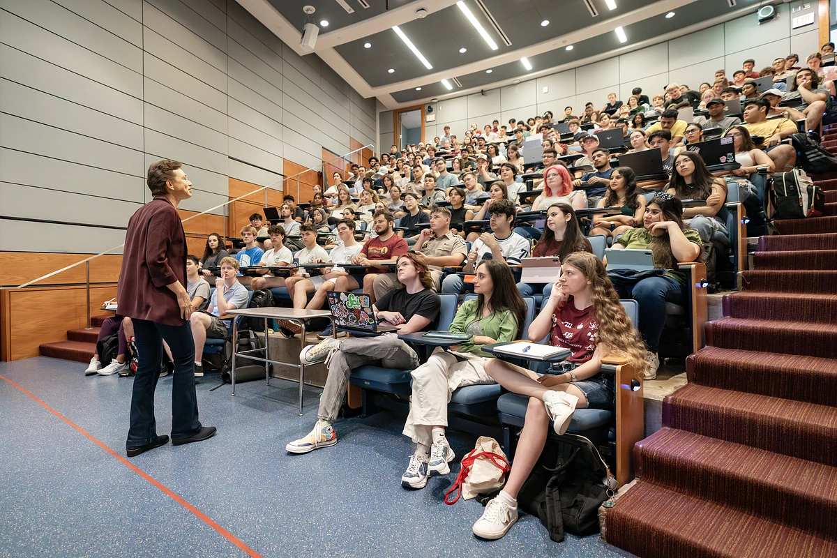 A professor lecturing to a group of students in a large classroom 