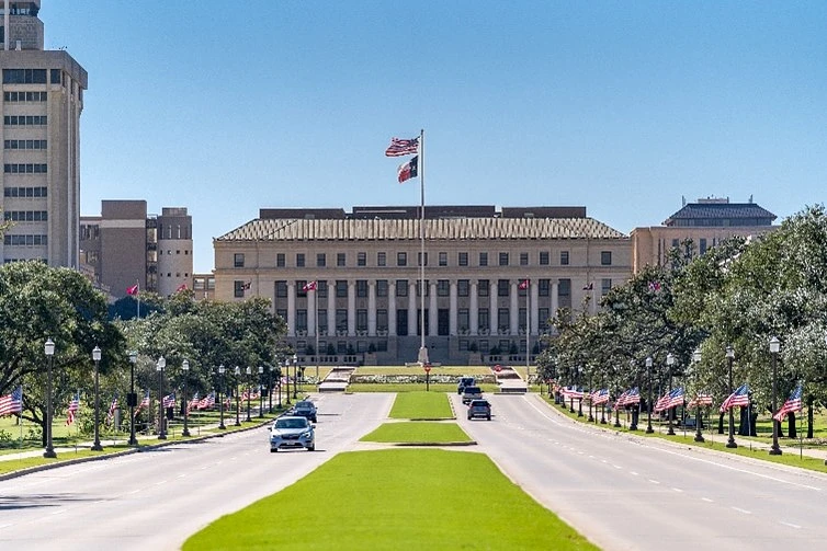 Photo of Administration Building with US Flag and State of Texas Flag. 